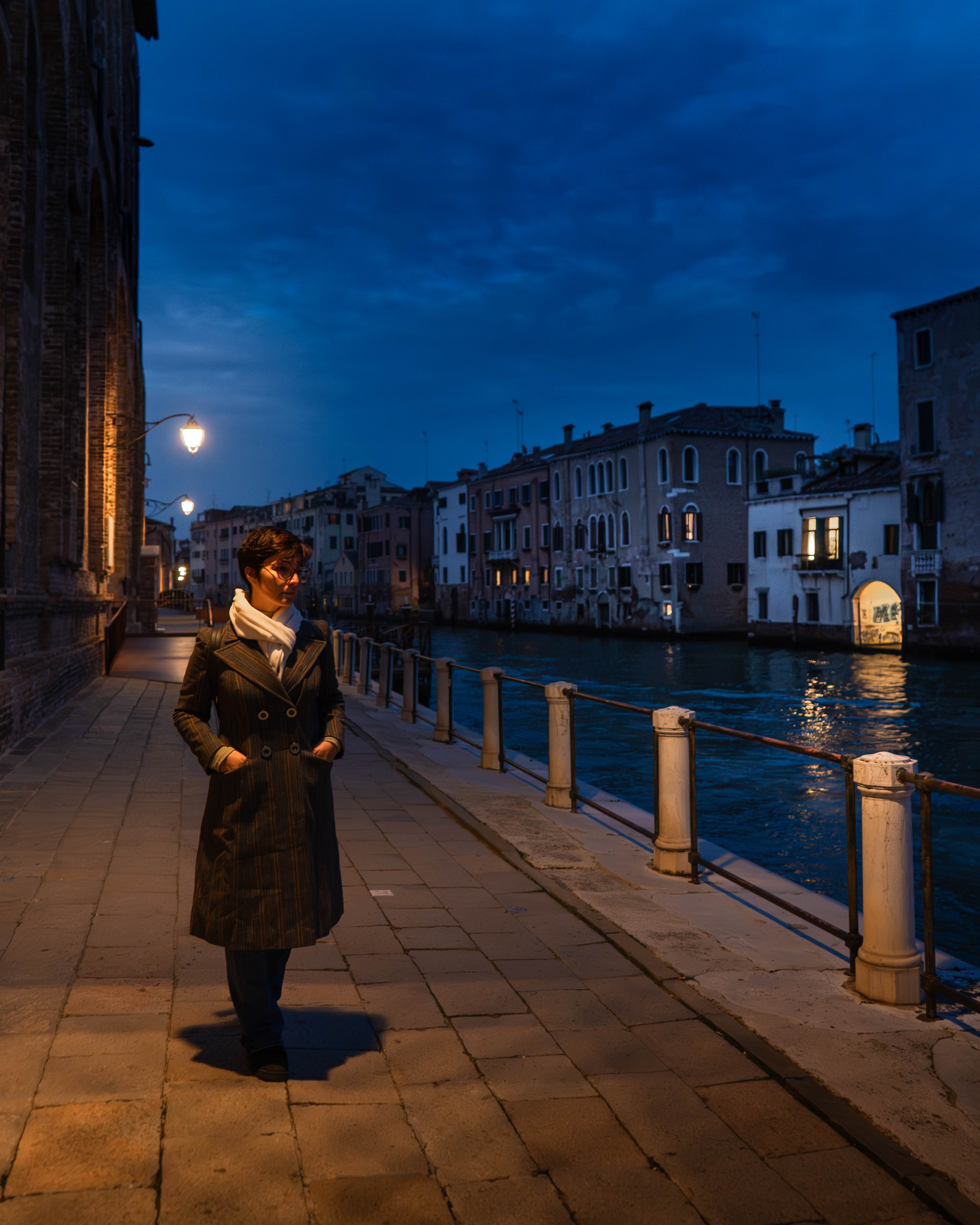 Mujer caminando por canal de noche — hora azul